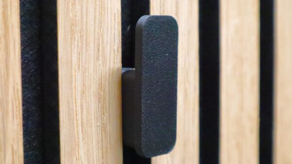 Minimalist black wall hook securely attached to acoustic panels, offering a modern and sleek design for hanging coats and accessories.