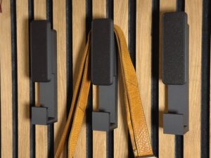 No-drill slat wall hanger holding leather bag on acoustic panel