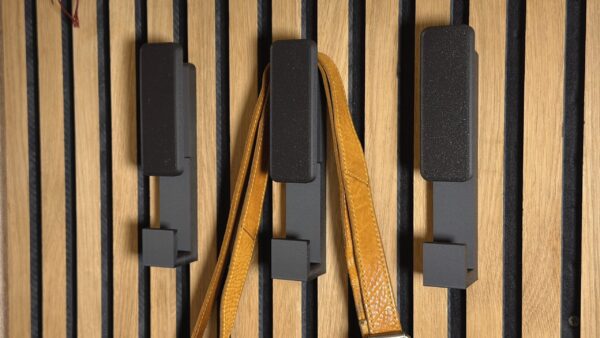 No-drill slat wall hanger holding leather bag on acoustic panel