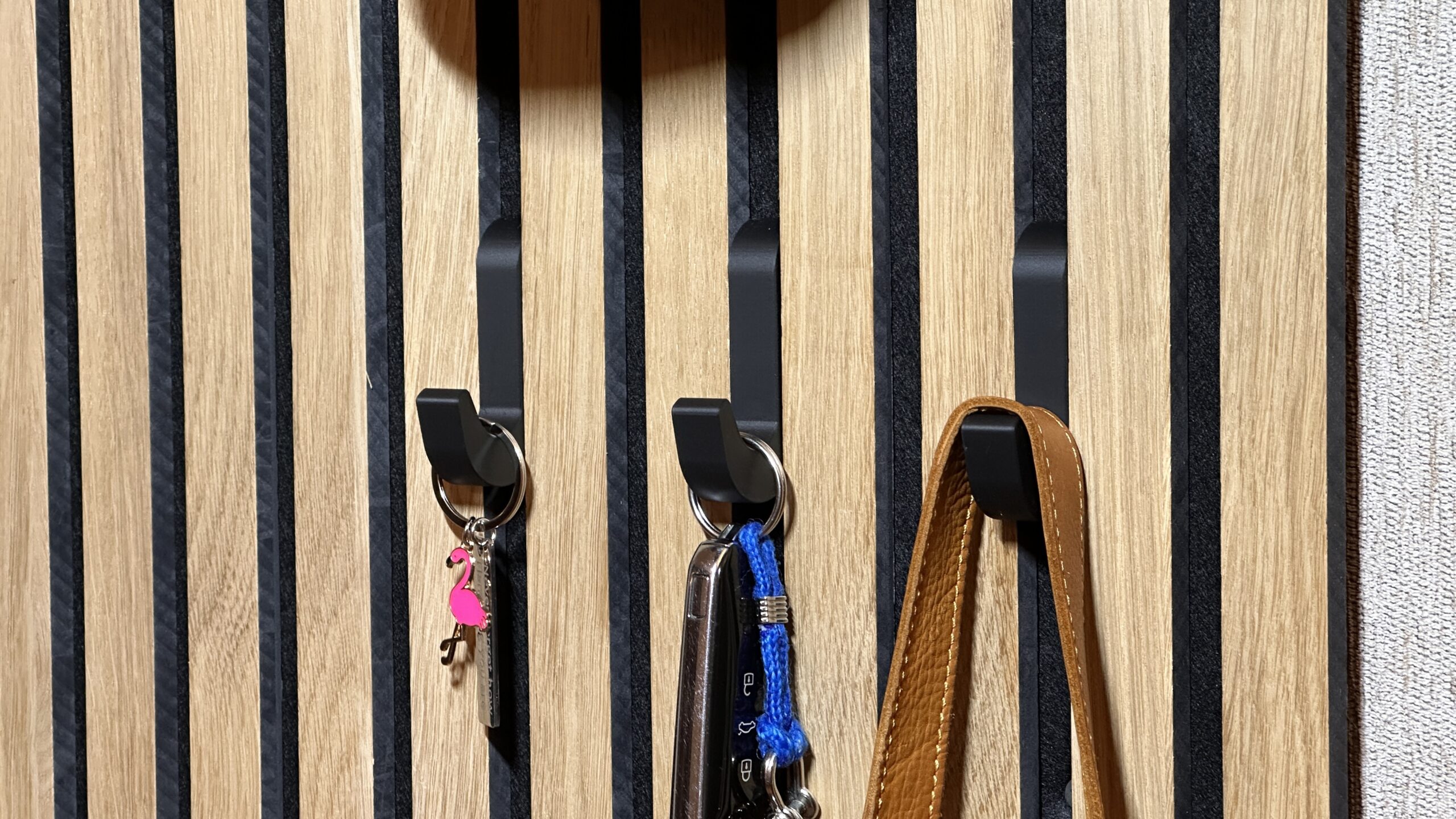 Headphones hanging from a curved hook fitted between wooden acoustic wall panel slats
