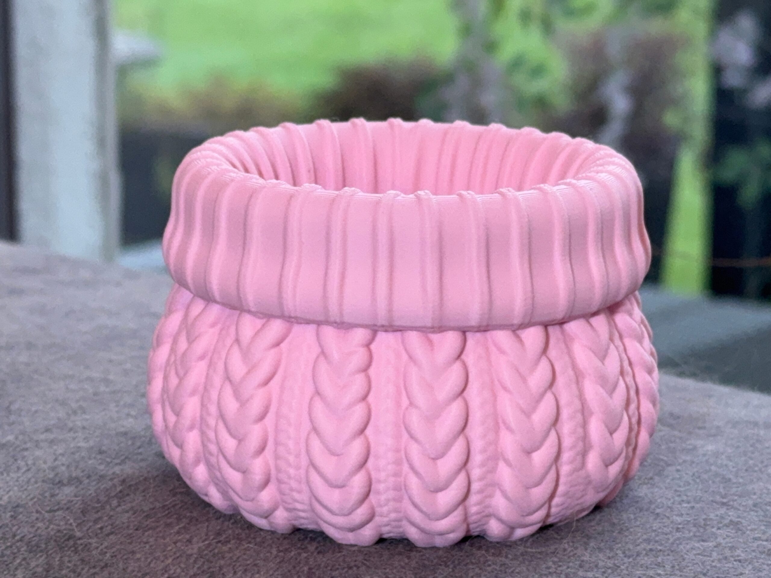 Close-up of a pink sweater planter showing the cable knit detailing and opening.