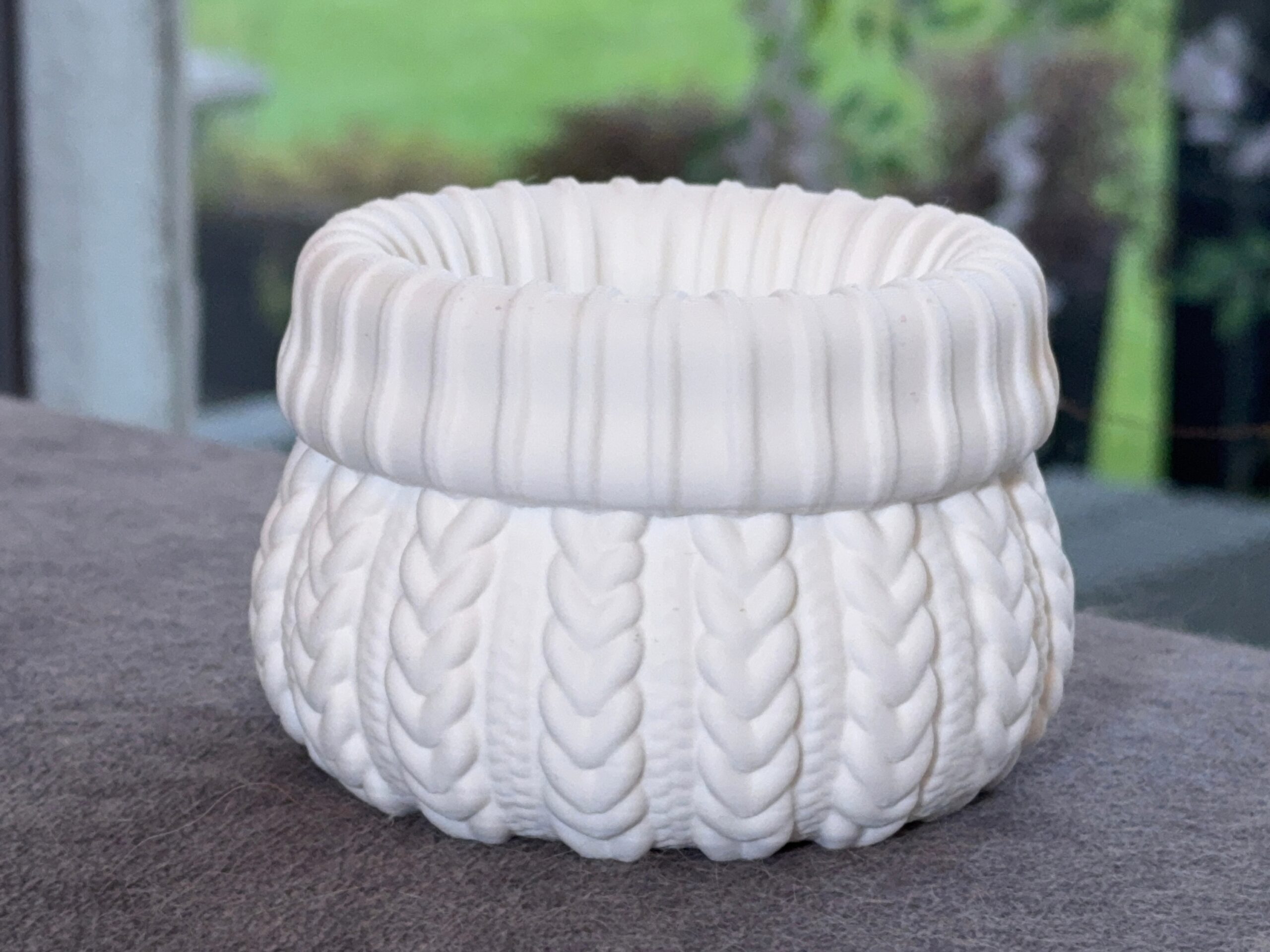 White cable knit planter showing its raised braid pattern and folded-look rim.