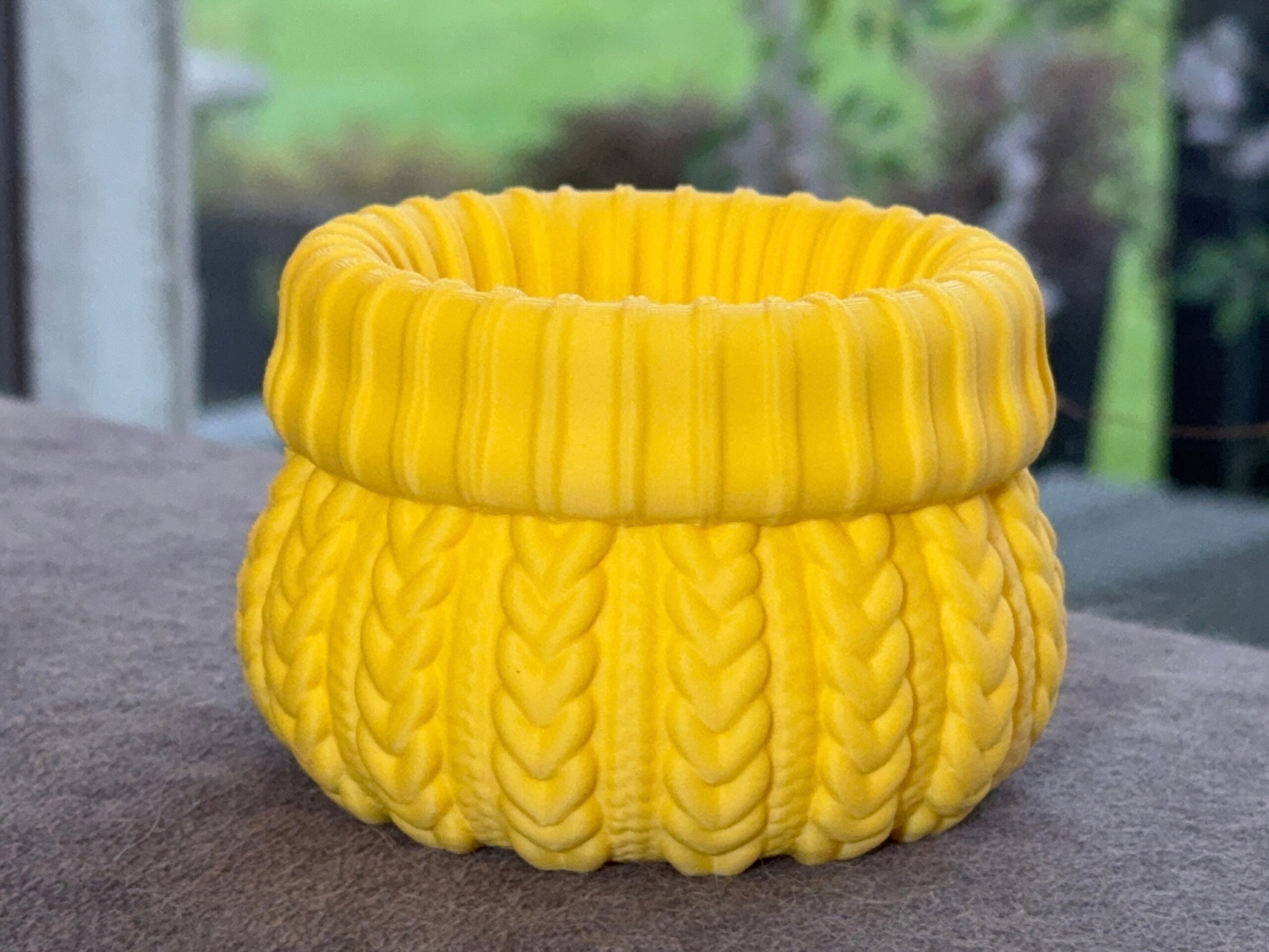 Empty yellow cable knit planter with a rounded body and thick ribbed rim.